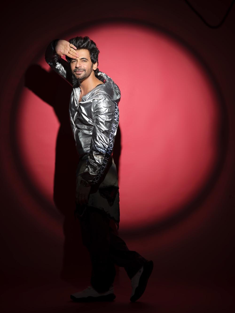 Sunil Grover in a silver jacket, caught mid-stride in a red spotlight